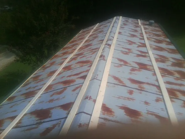 Rusted metal roof panels with new wood purlins before replacement — Storm Damage Roof Repair in Carnesville by Roofing Brothers