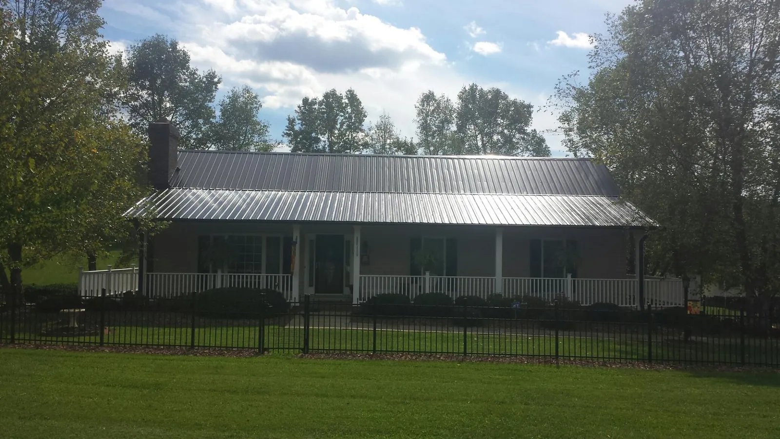 Gray metal roof on a brick ranch with a full width front porch — Gutter Guard Installation work by our crew in Carnesville