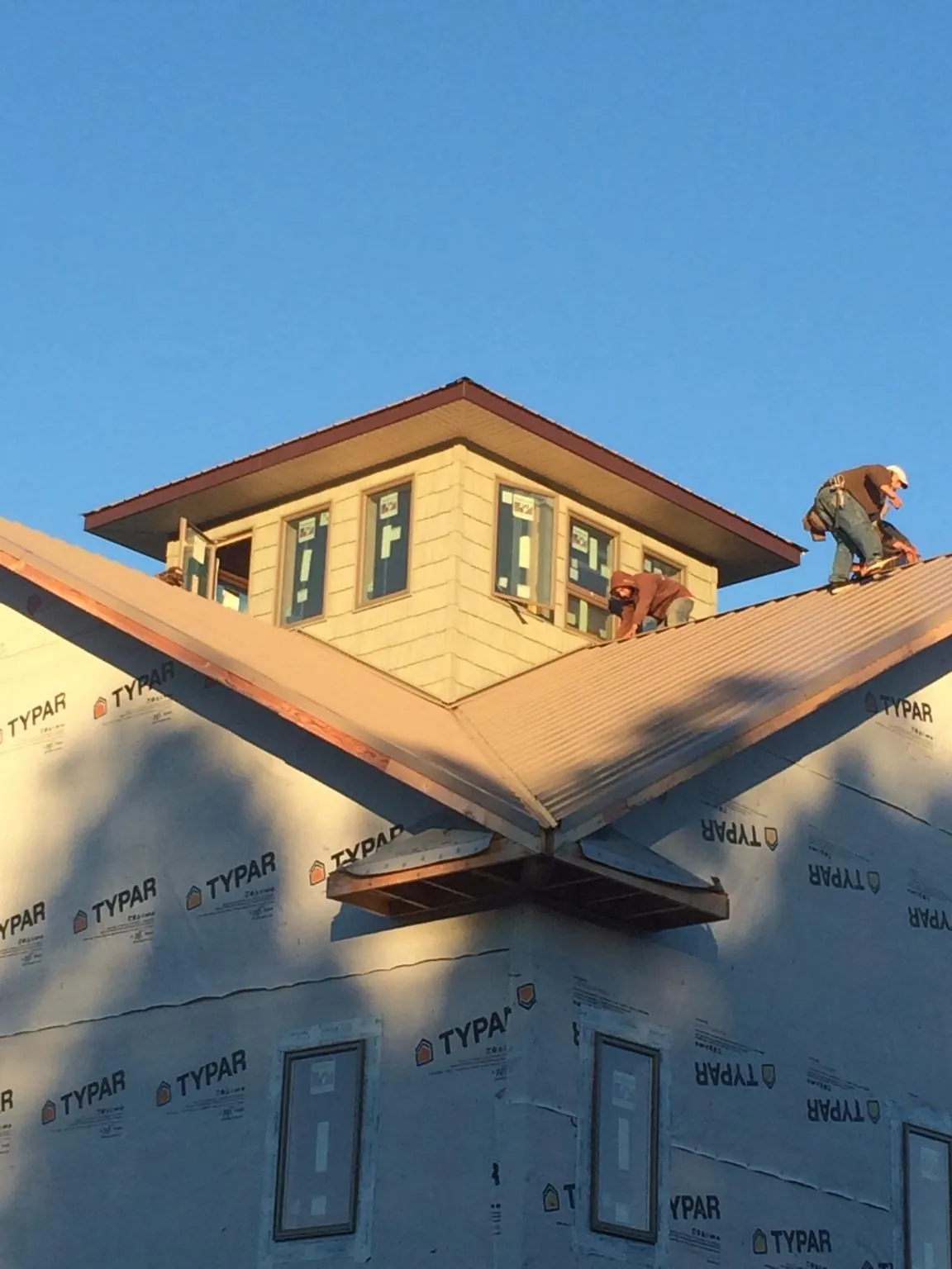 Roofers working around a rooftop cupola on a new metal roof at sunset — Roof Waterproofing in Carnesville by Roofing Brothers